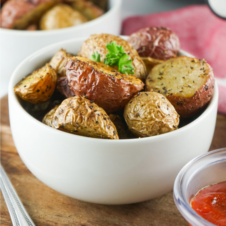 Bowl of roasted potatoes garnished with parsley.