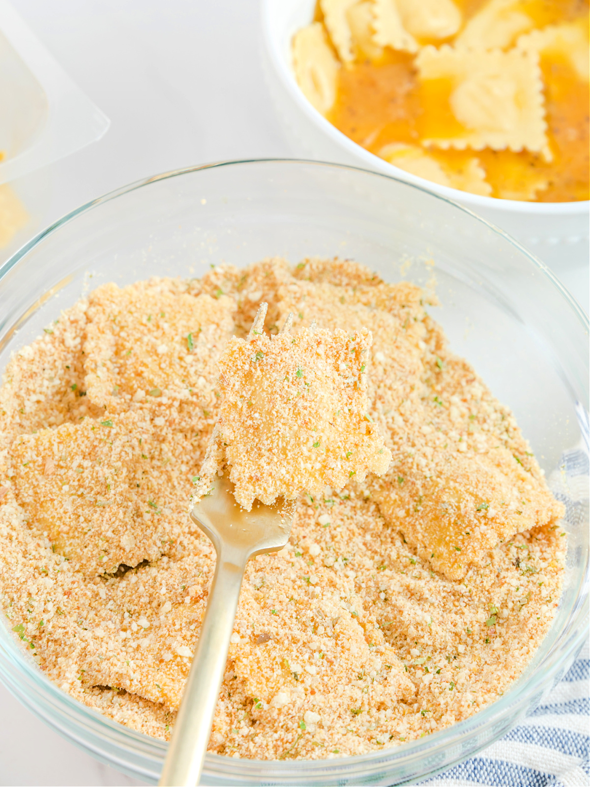 Ravioli being coated in a breadcrumb mixture.