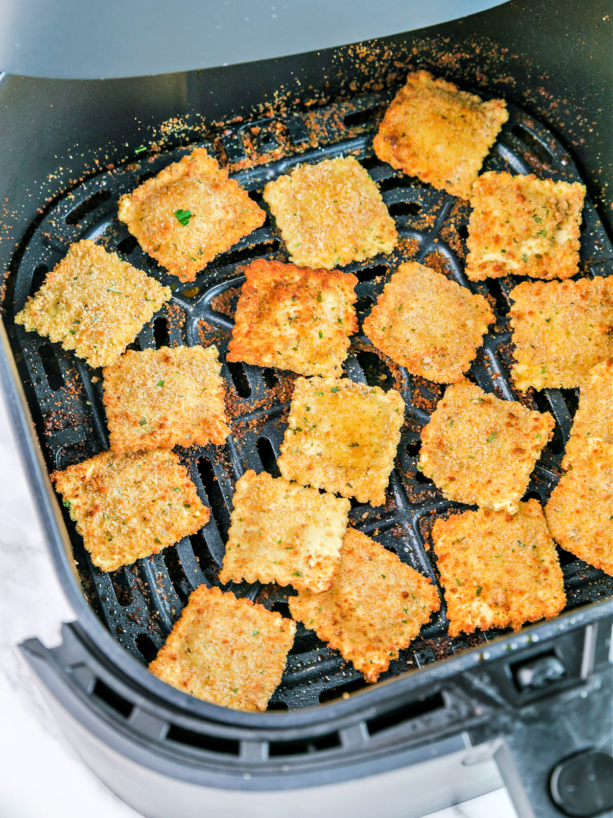 Ravioli being toasted in an air fryer.