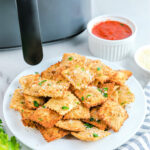 Plate of toasted ravioli and small bowl of marinara sauce.