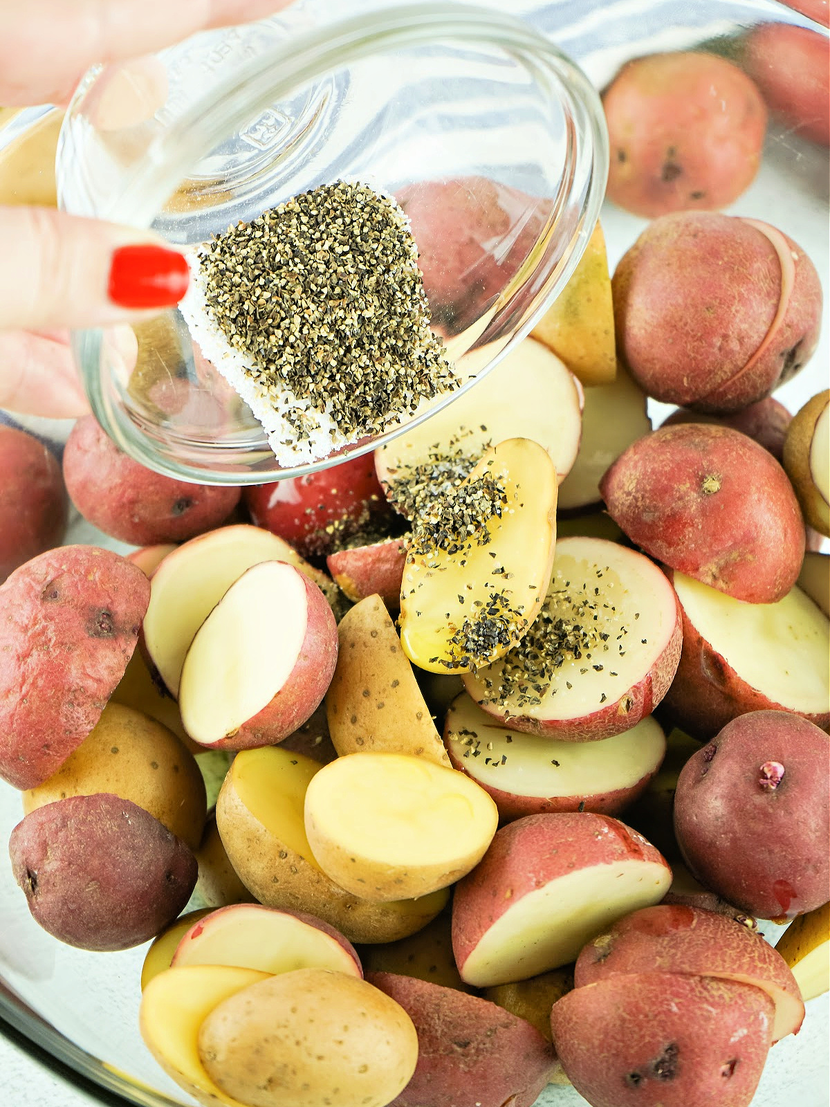 Salt and pepper being sprinkled onto potato slices.