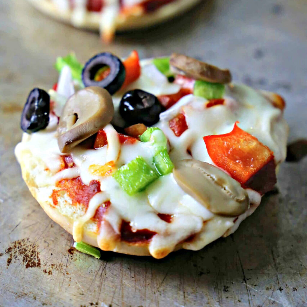 Veggie bagel pizza on a baking sheet.