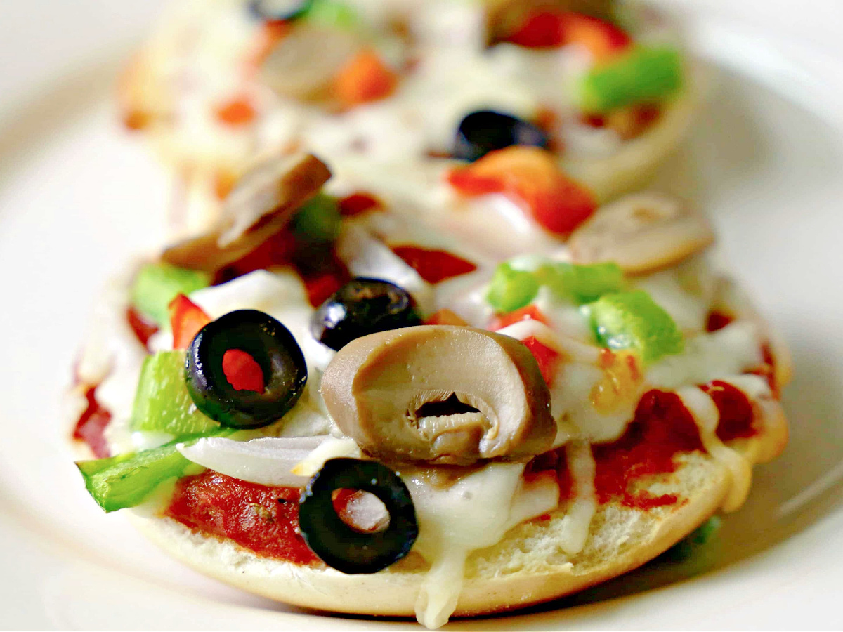 Veggie bagel pizza on a plate.