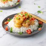 Bowl of bang bang shrimp and rice topped with green onions and diced tomatoes.