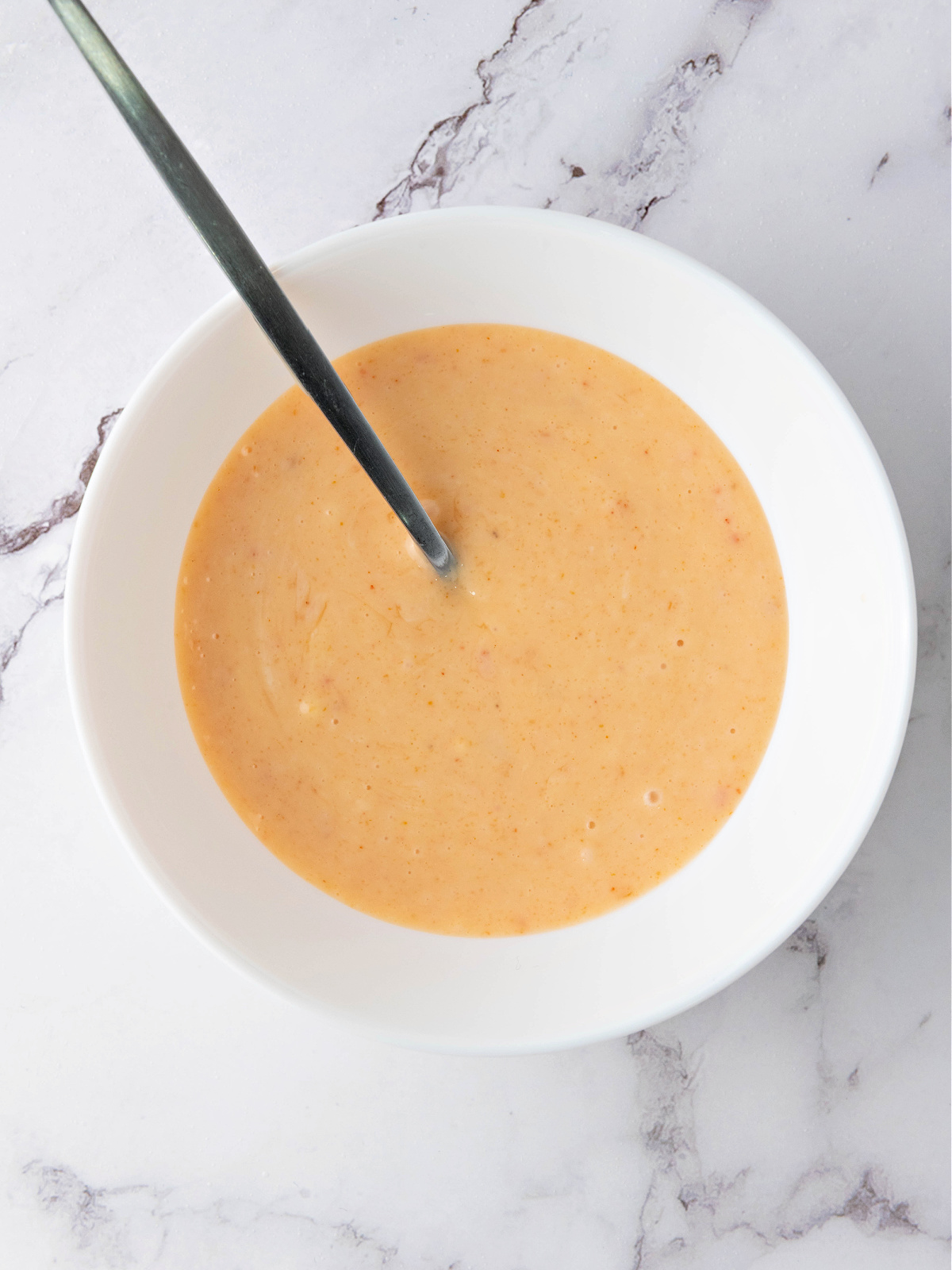 Homemade bang bang sauce in a bowl with a spoon.