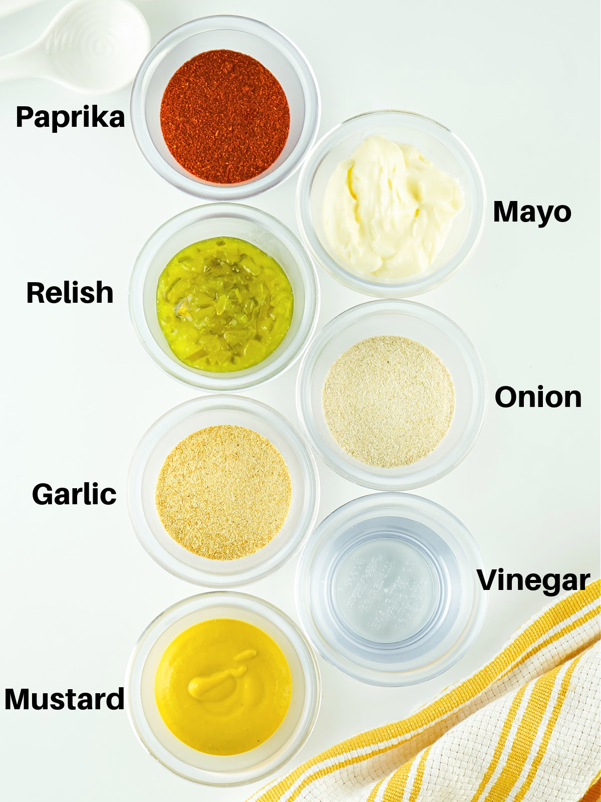 Small bowls filled with paprika, mayonnaise, relish, onion powder, garlic powder, vinegar, and mustard.