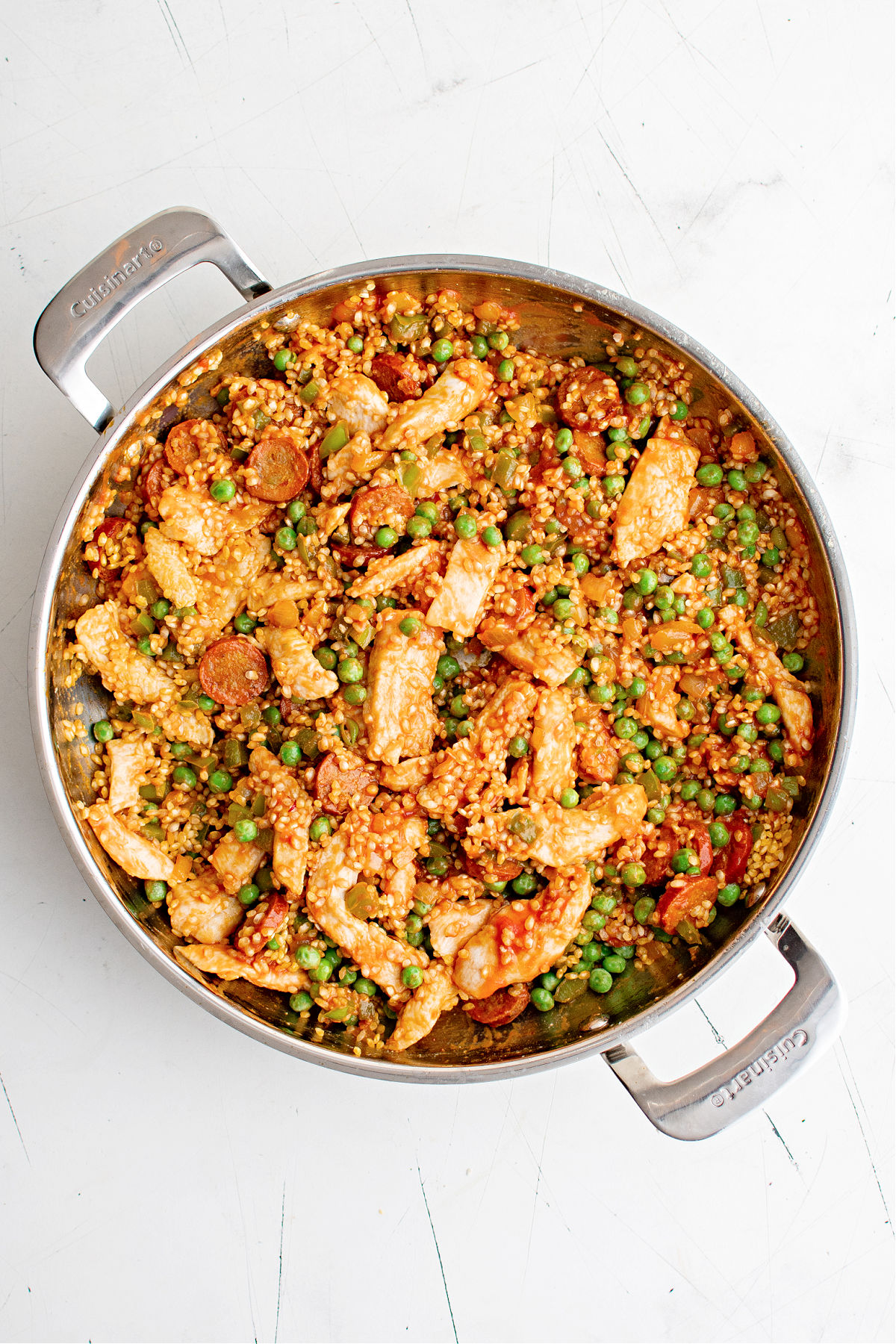 Chicken paella cooking in a skillet.