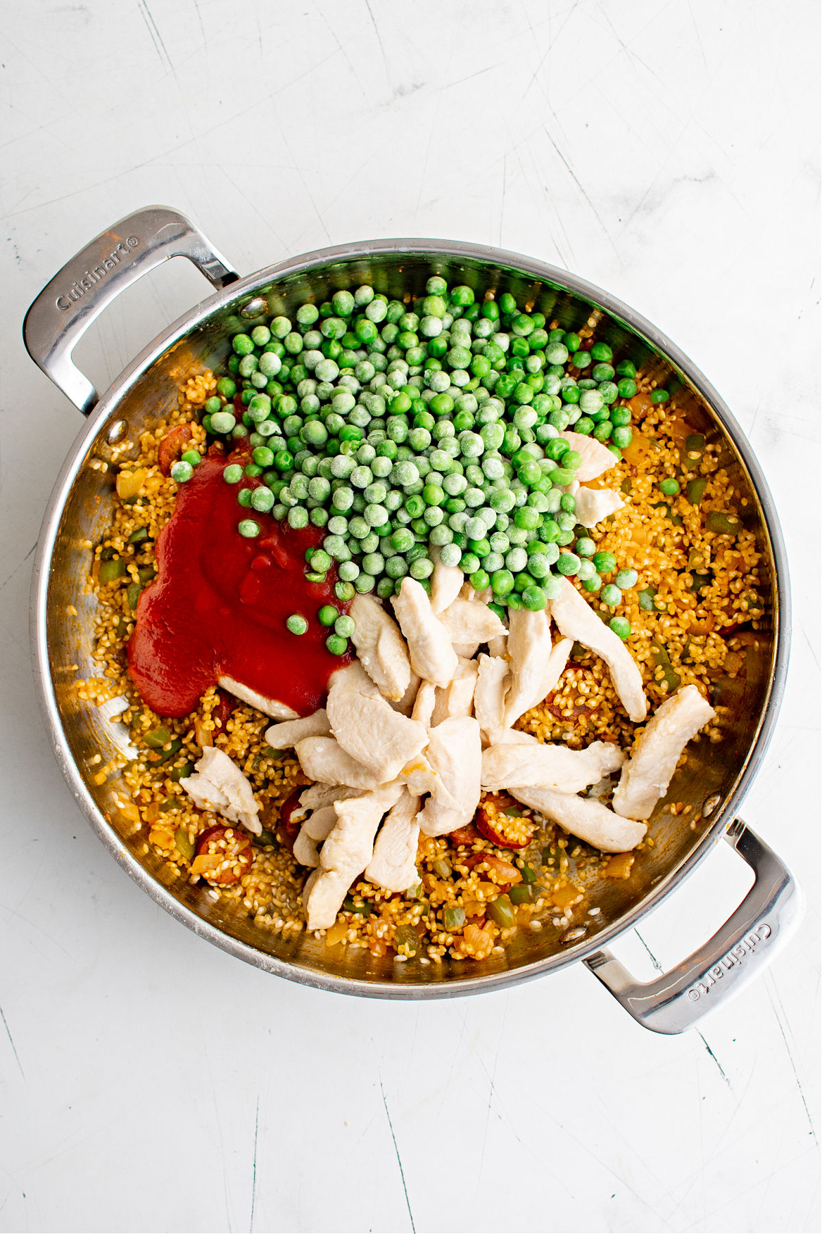 English peas, chicken and sauce in a skillet.