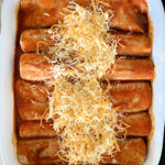 Chicken enchiladas covered with shredded cheese.