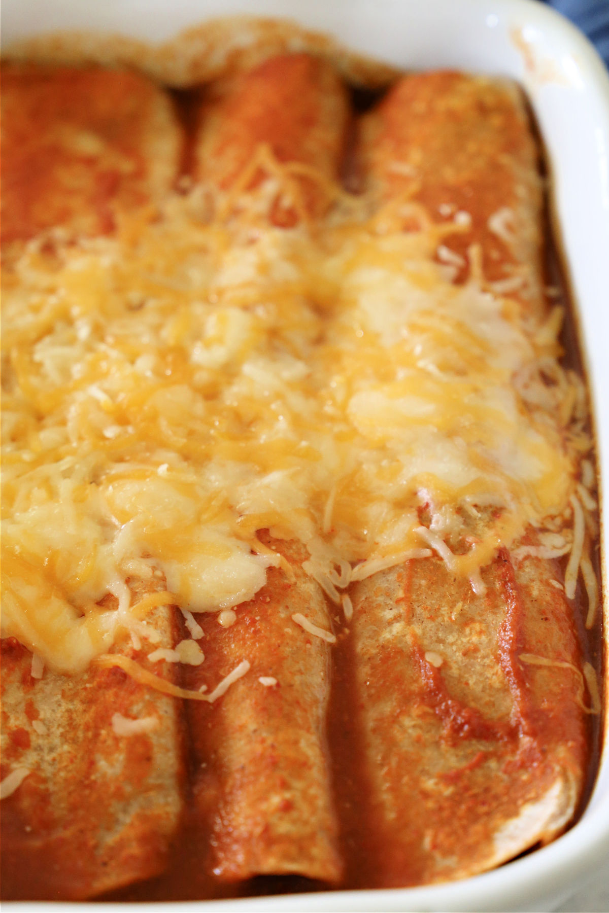 Cheesy enchiladas with a red sauce in a baking dish.