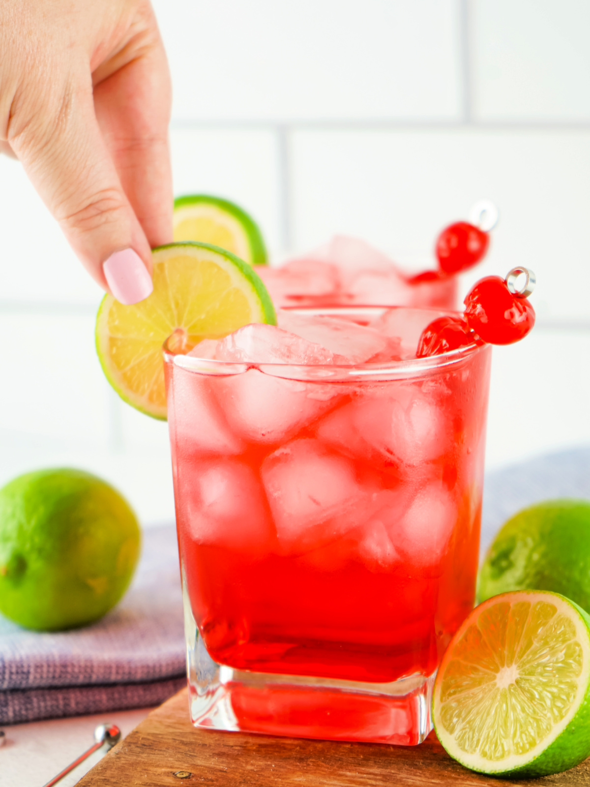 Woman's hand placing a lime wheel on a cocktail glass.