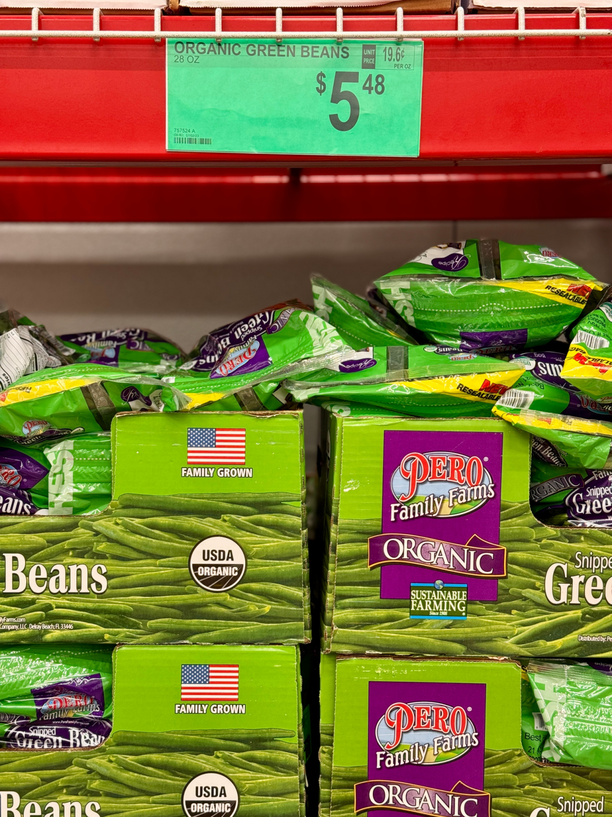 Bags of organic green beans for sale with a sign indicating that the prices is $5.48.