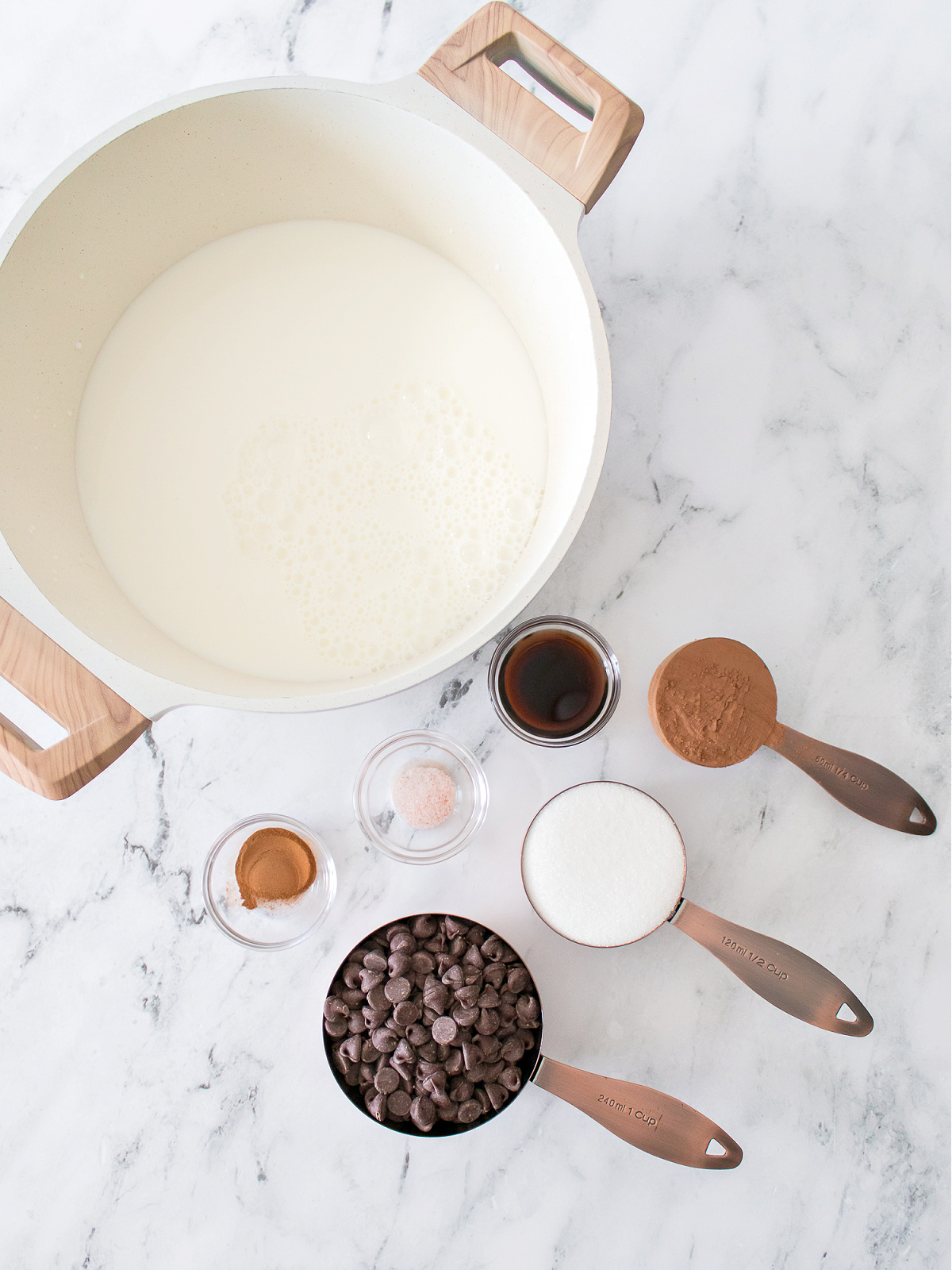 Pot of milk, cinnamon, vanilla, salt, chocolate chips, sugar, and cocoa powder.