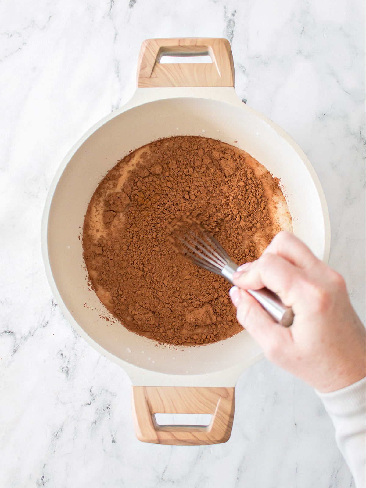 Whisking cocoa powder, cinnamon, and salt together in a pot of milk.