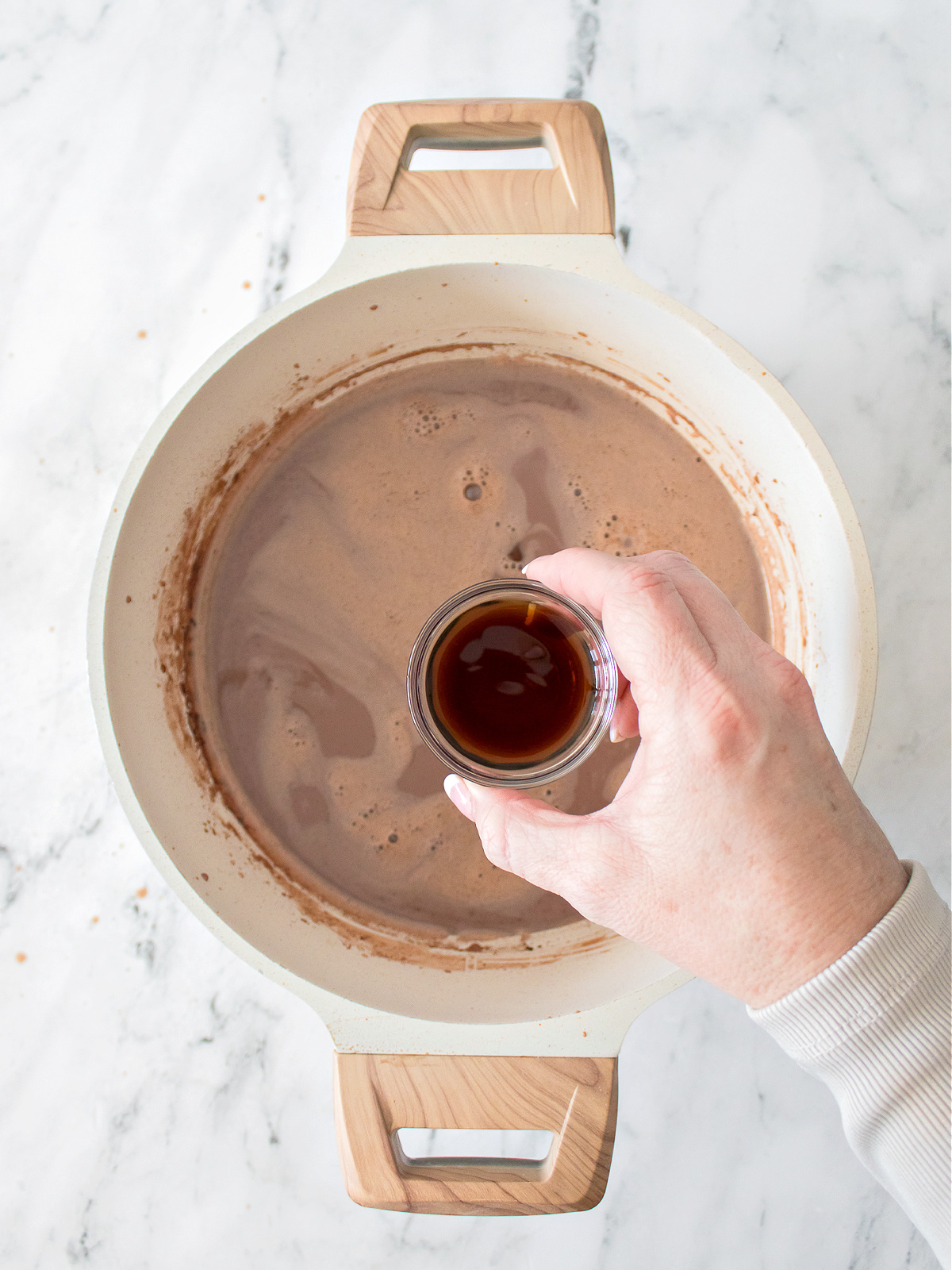 Adding vanilla to a pot of hot chocolate.