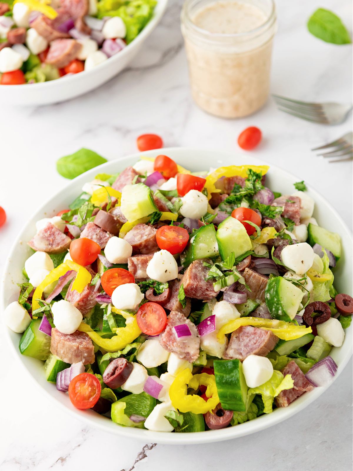 A serving of Italian Chopped Salad and a glass jar filed with dressing.