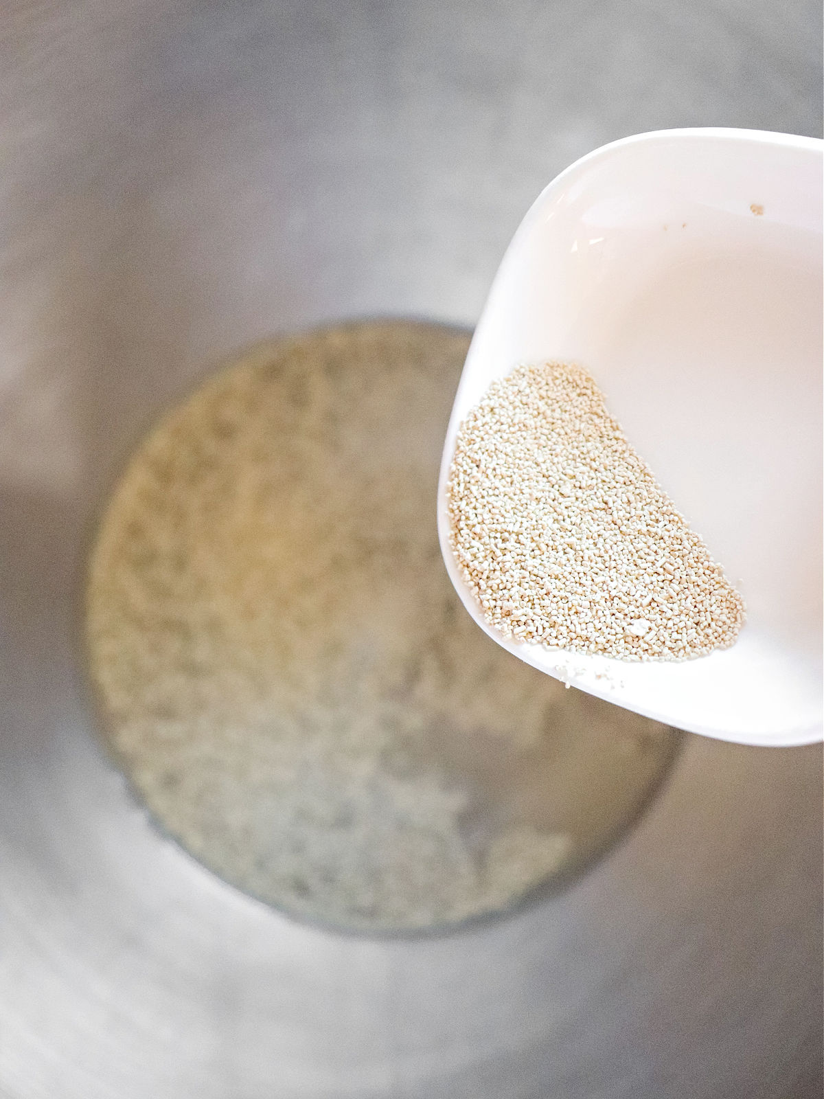 Adding yeast to warm water in a metal bowl.