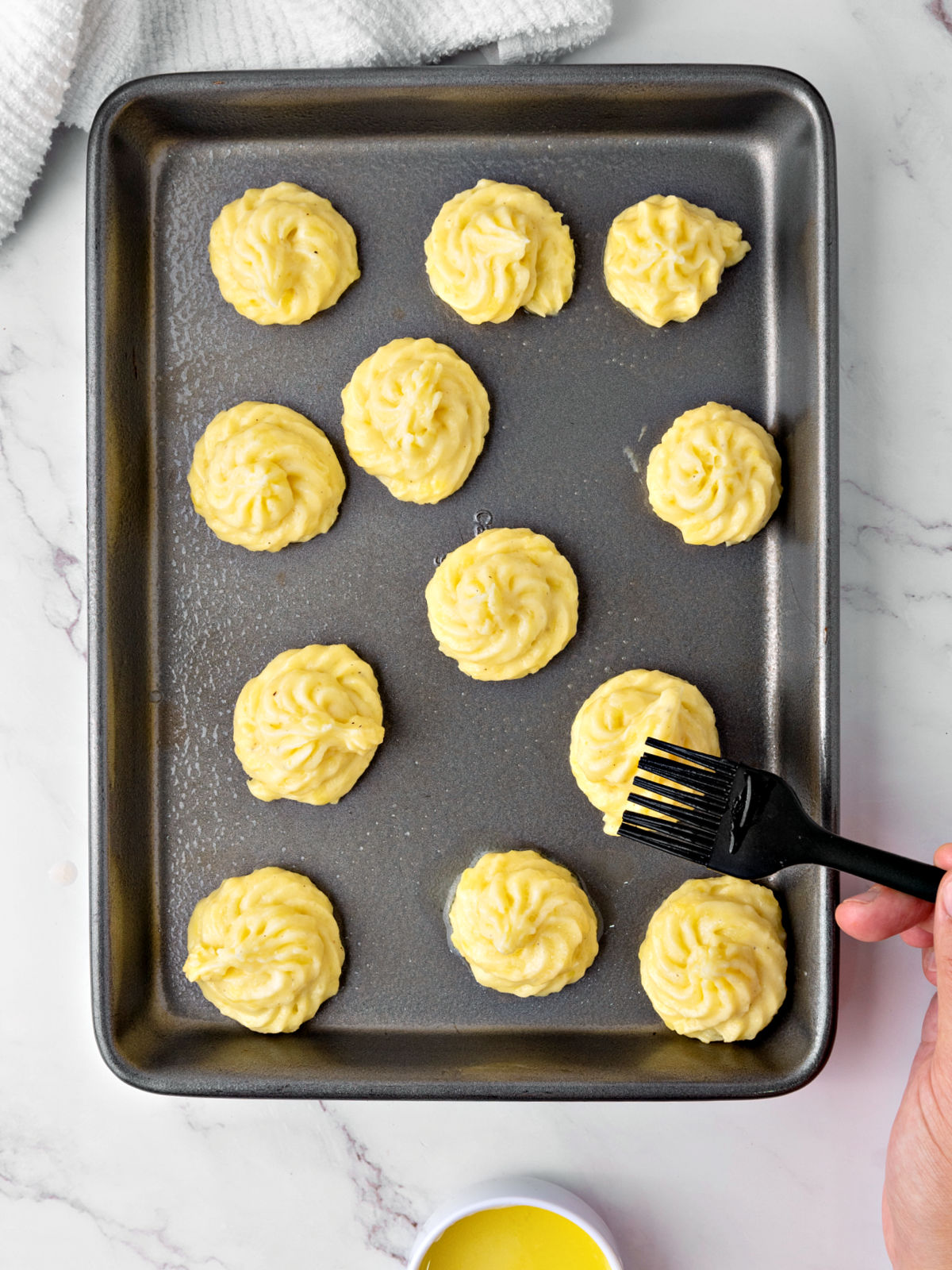 Brushing pommes duchesse with butter.