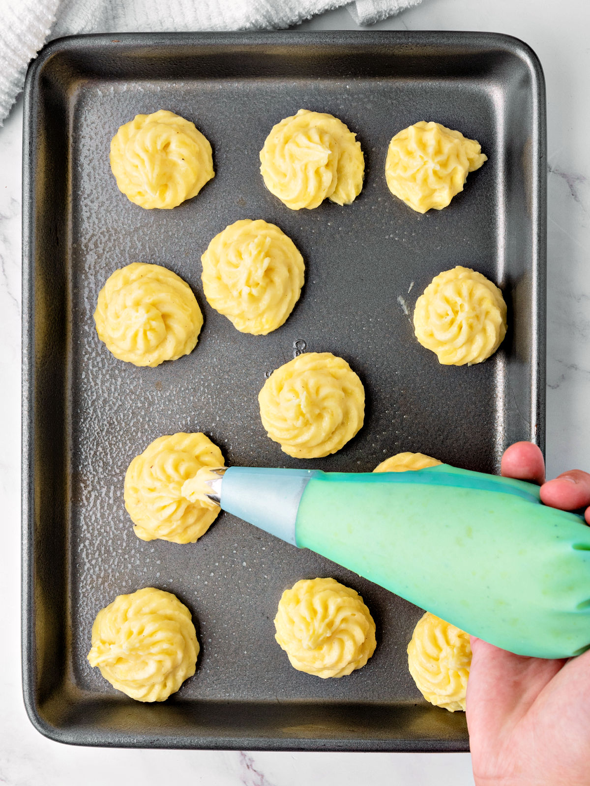 Piping potatoes on a cookie sheet.