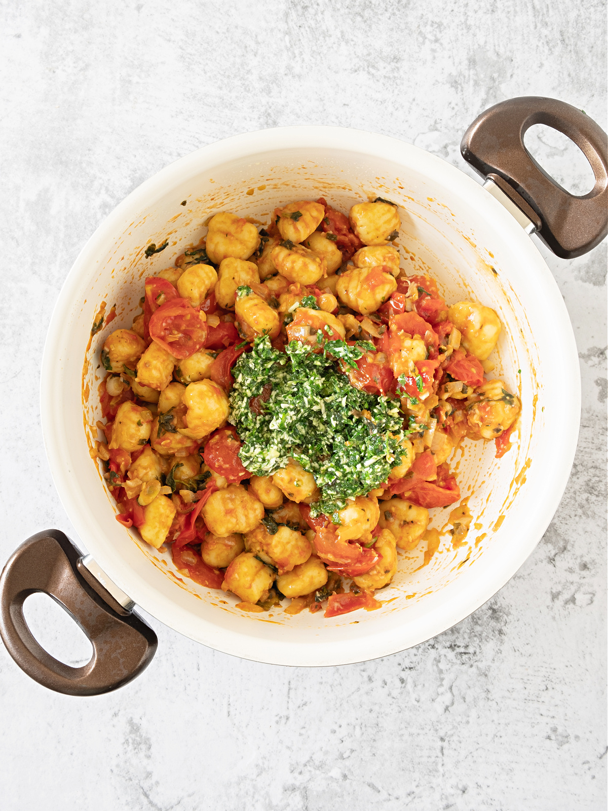 Pot of gnocchi with tomatoes and herbs.