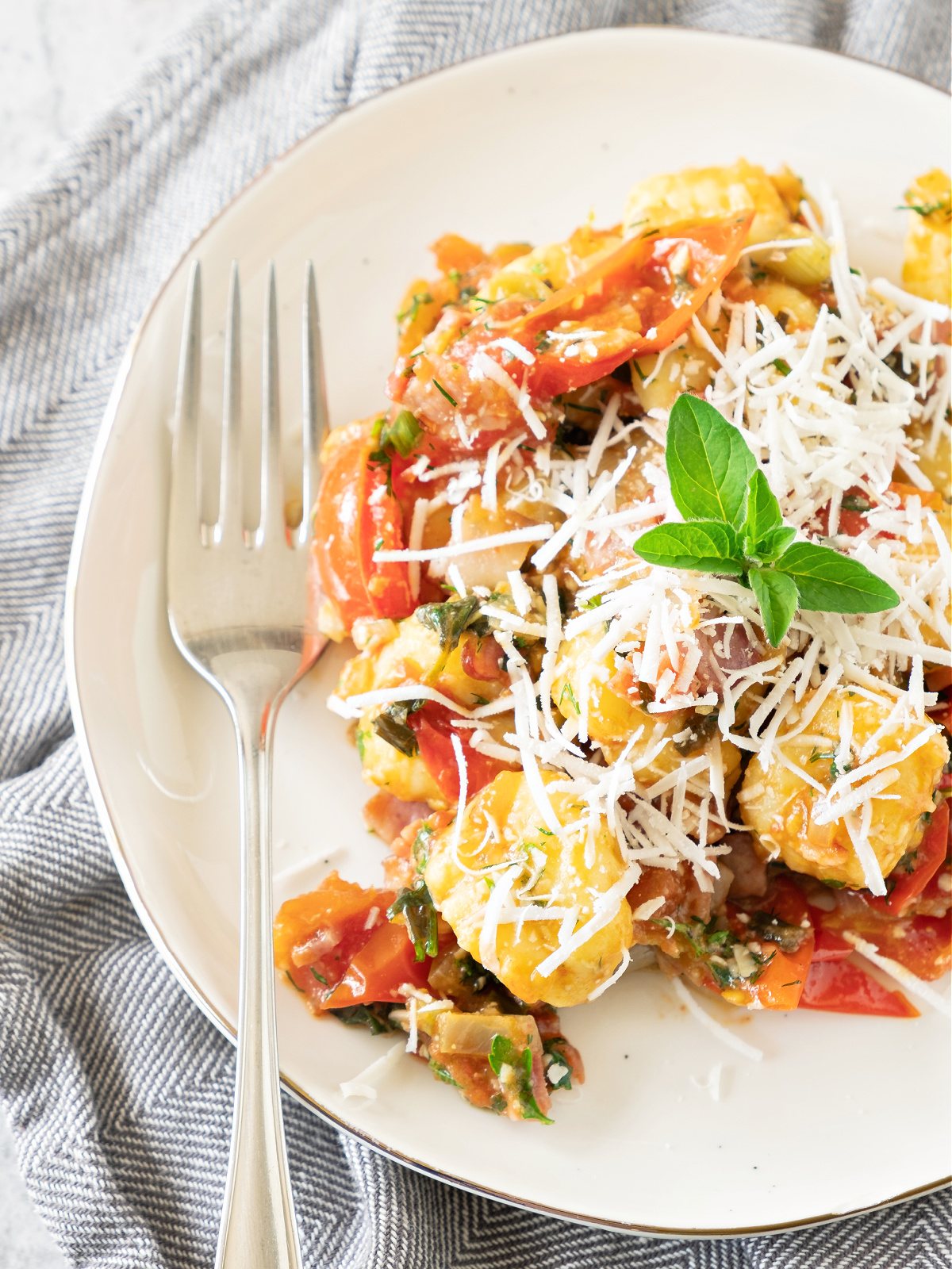 Plate of potato gnocchi with bacon and tomatoes.