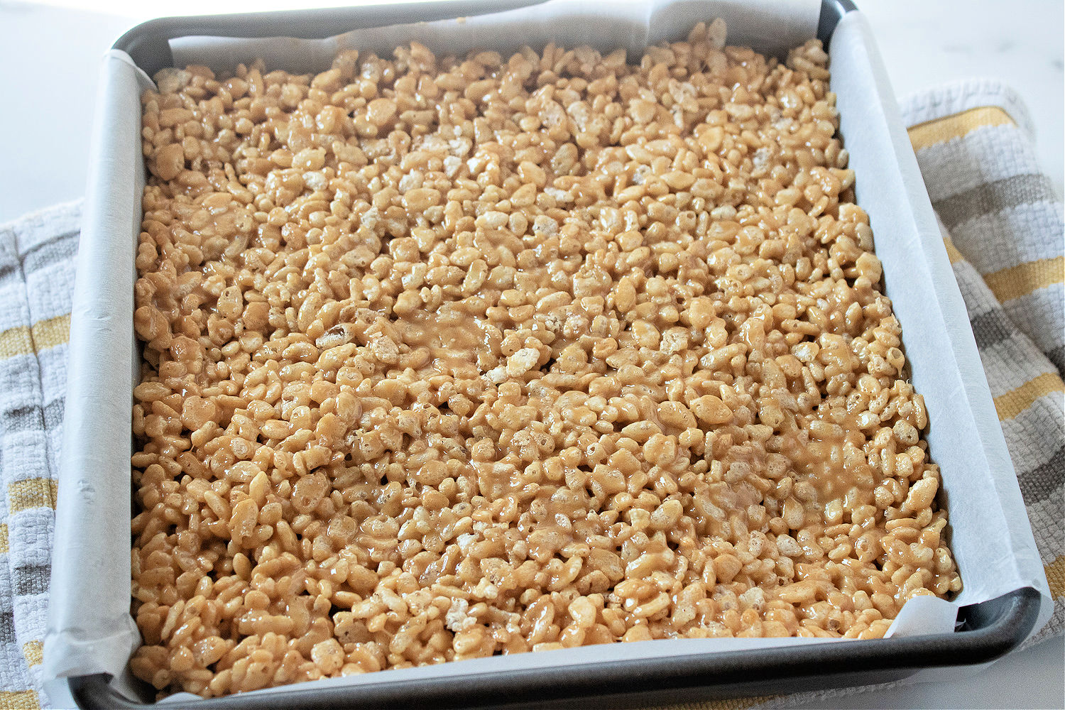 Peanut butter Rice Krispies in a metal baking pan.