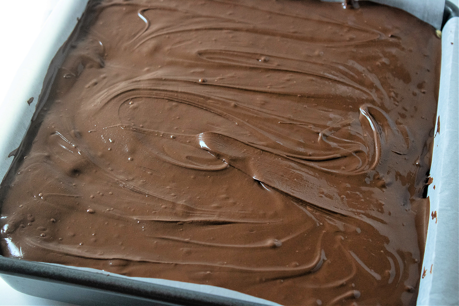 Chocolate frosted Rice Krispies treats in a pan.