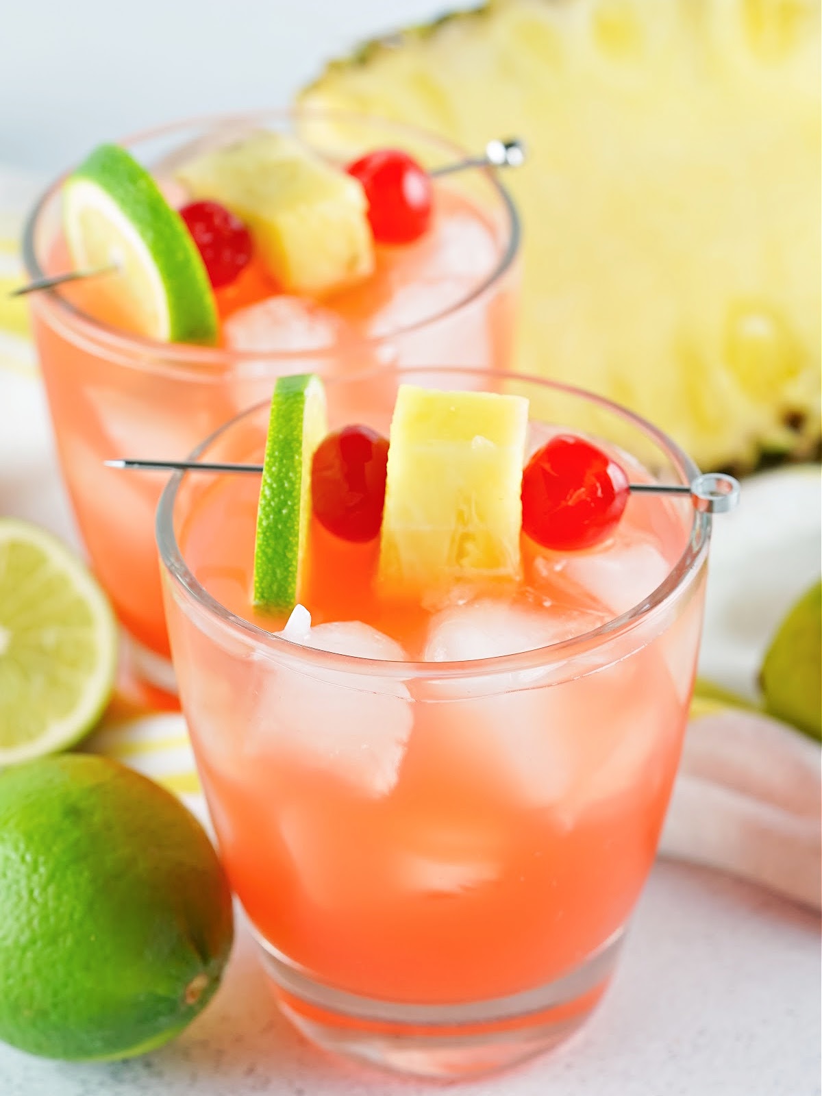 Rum punch garnished with lime, pineapple, and cherries.