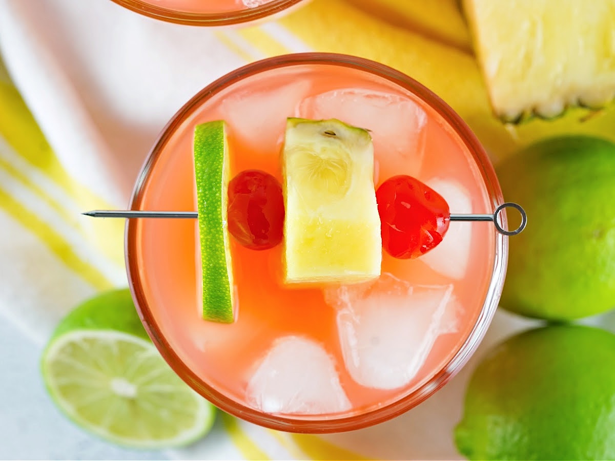 Lime, cherries, and pineapple garnishing a glass of rum punch.