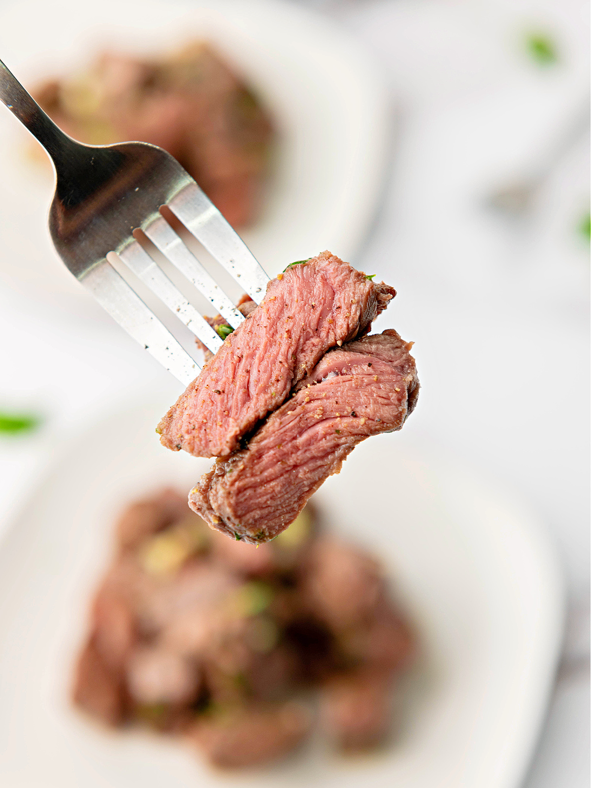 Pieces of steak on the end of a fork.