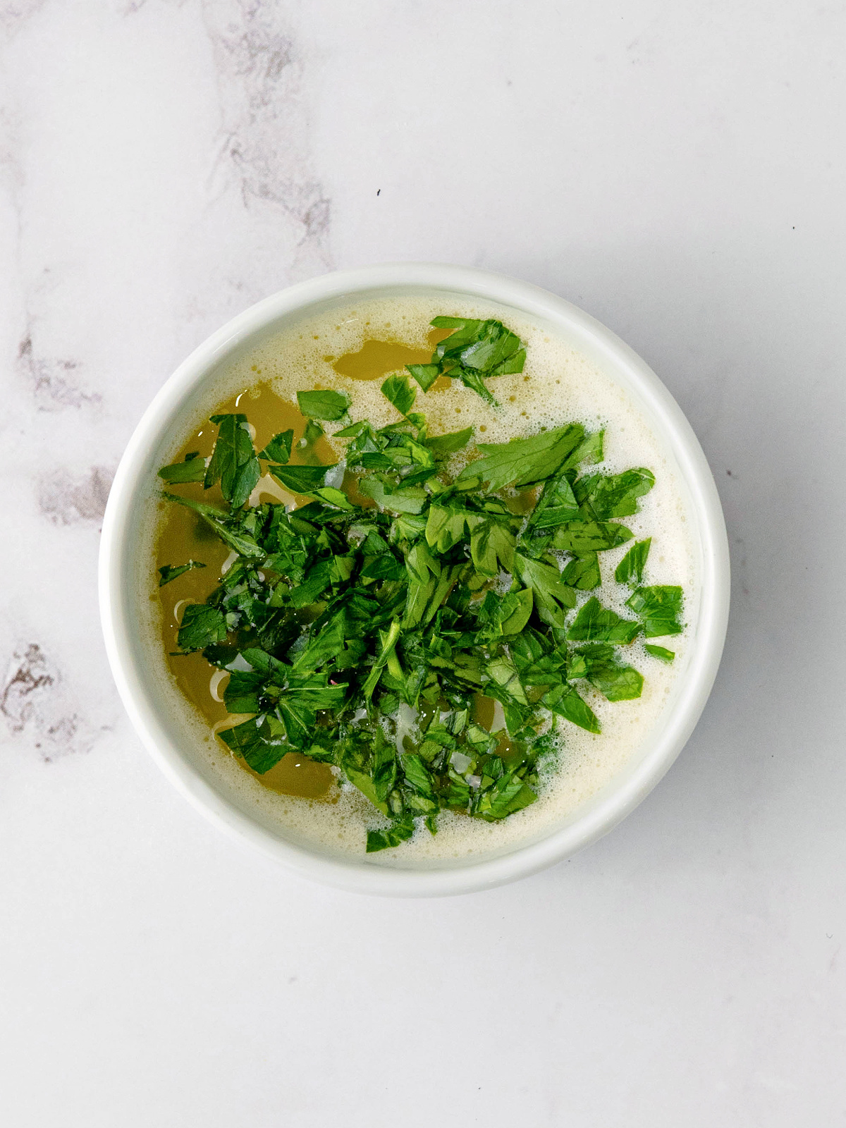 Melted butter and herbs in a small bowl.