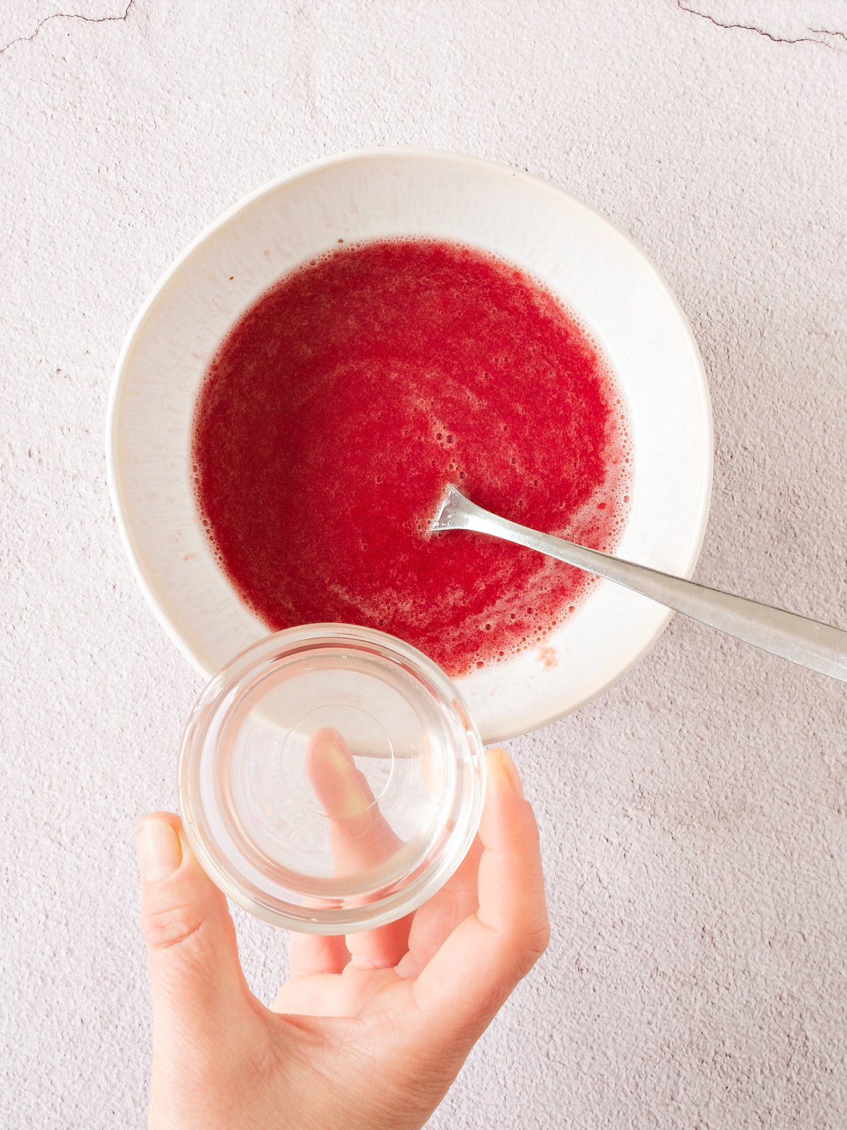 Dissolved gelatin being added to pureed strawberries.