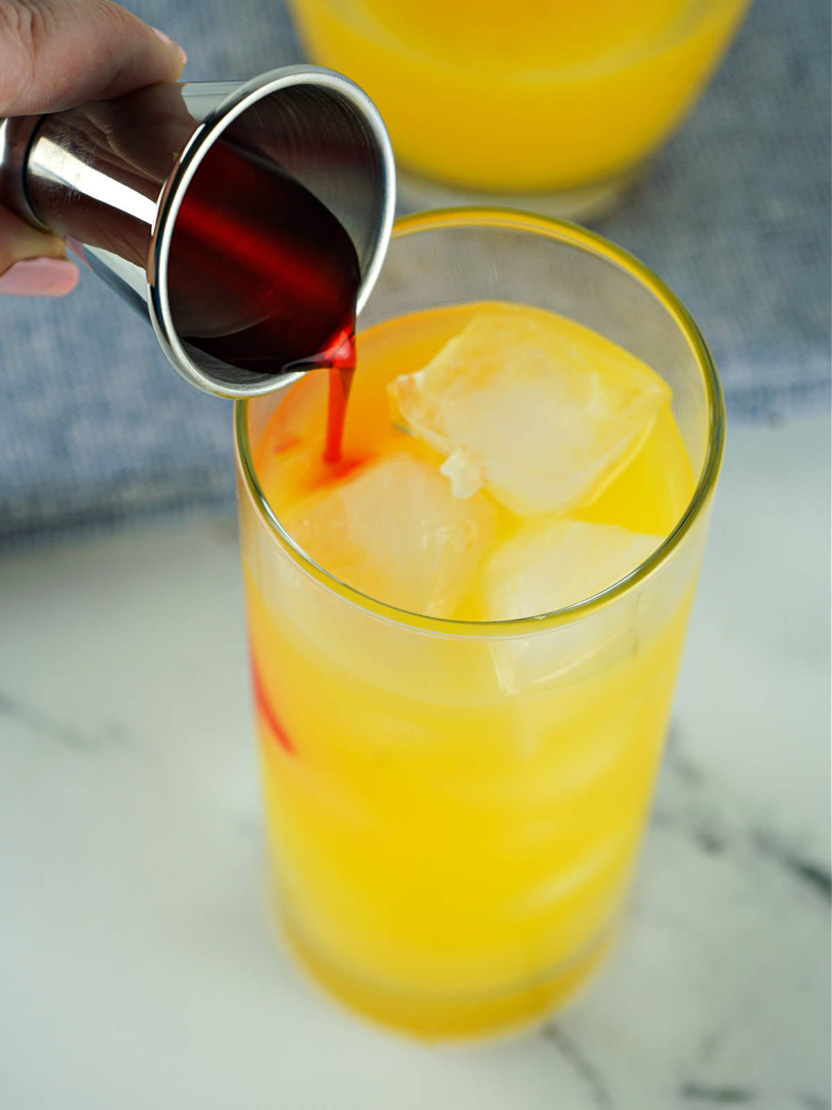 Grenadine syrup being poured into a glass.