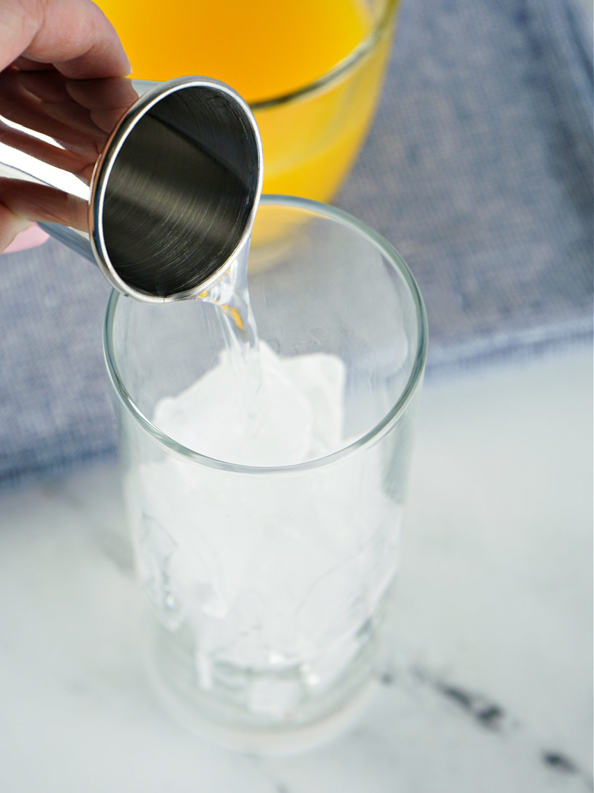 Tequila being poured into a glass with ice.