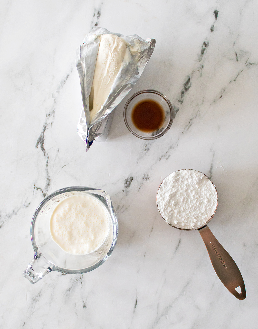 Block of cream cheese, vanilla extract, heavy whipping cream, and powdered sugar.