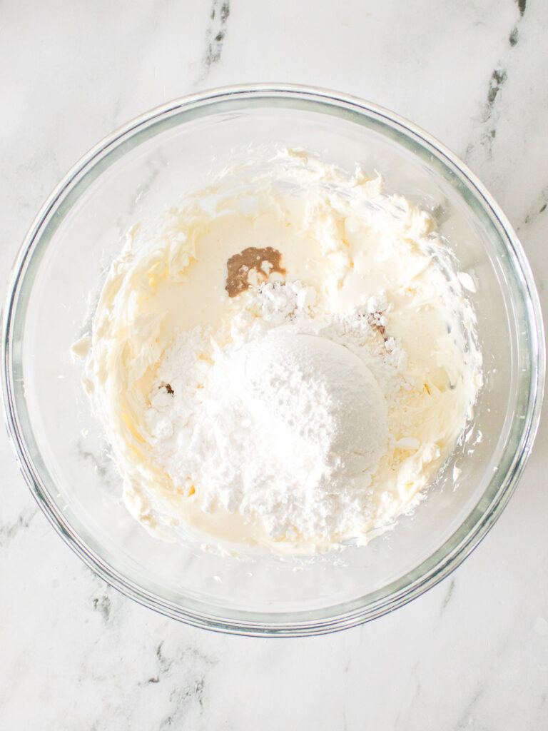 Cream cheese, heavy whipping cream, powdered sugar, and vanilla extract in a mixing bowl.