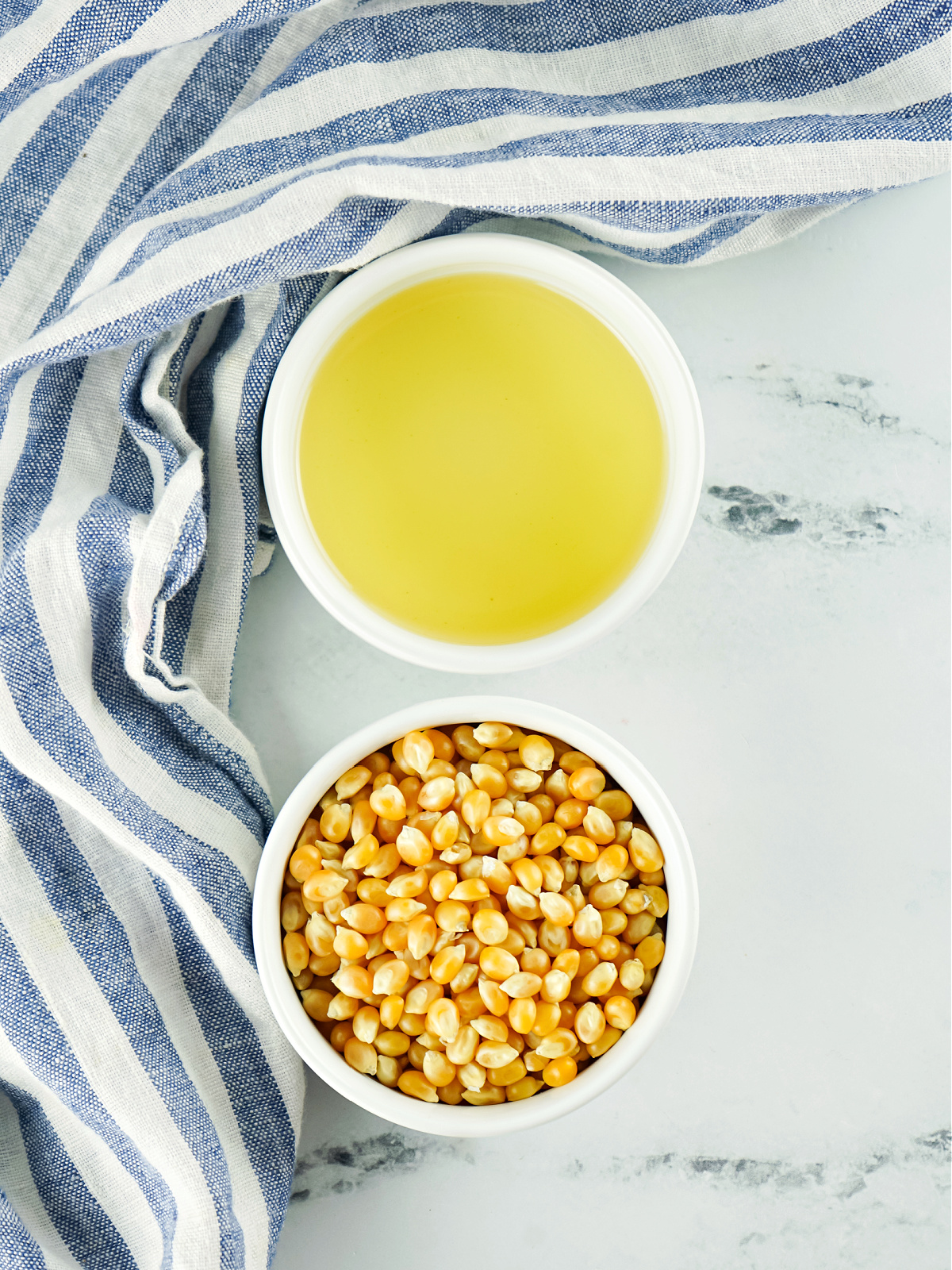 Small bowls of oil and popcorn kernels.