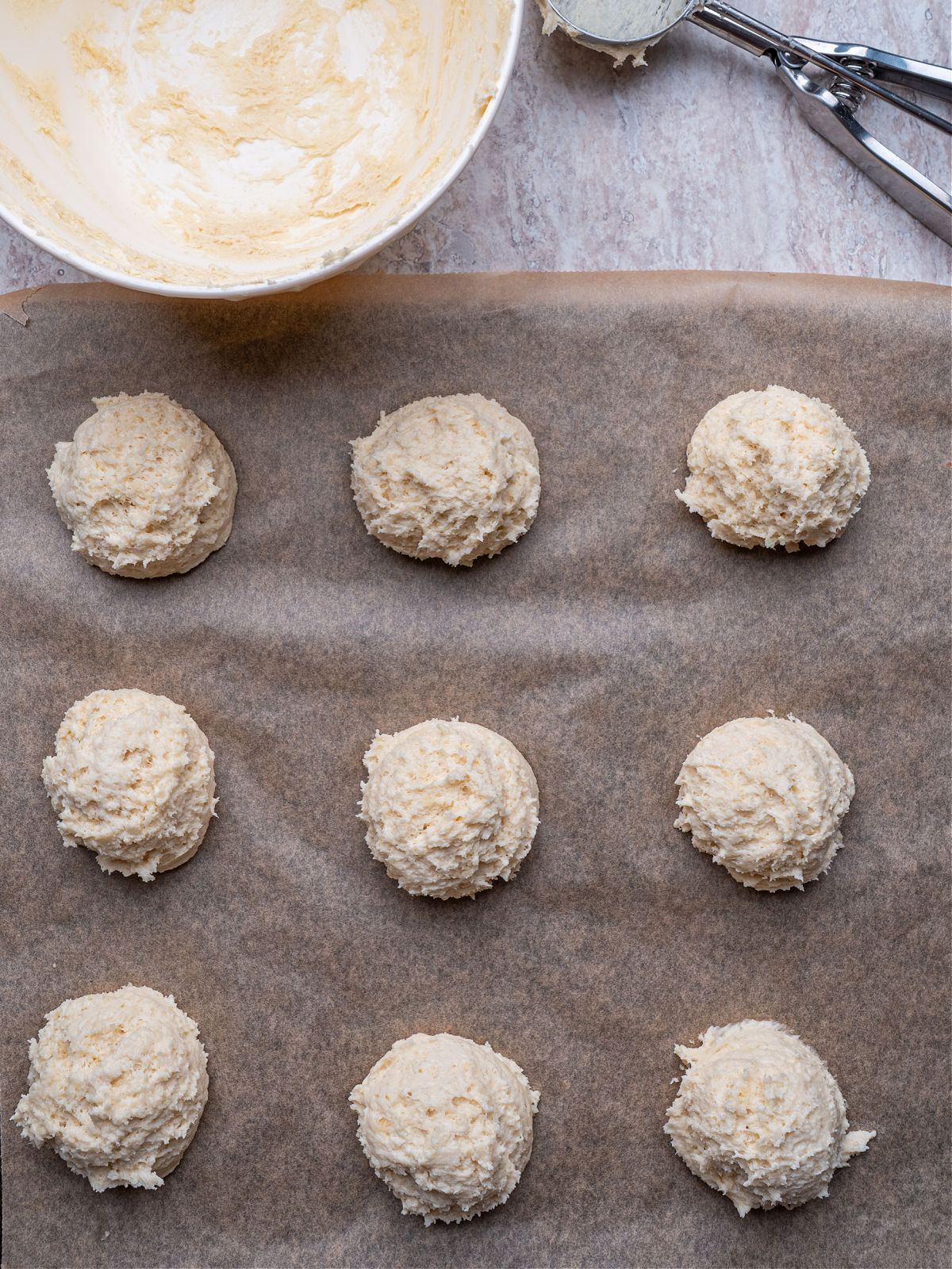 Biscuit dough dropped onto a parchment lined baking sheet.